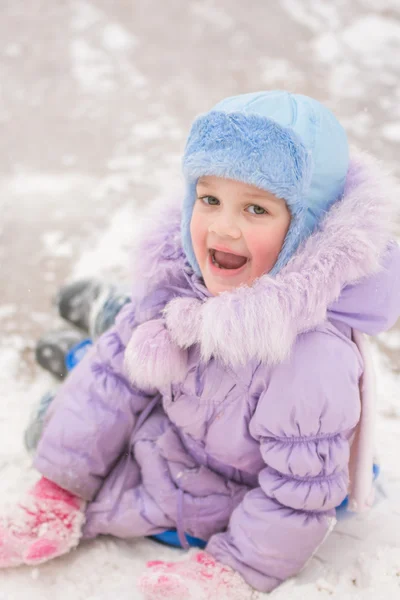 Funny five-year girl sitting rolled down an ice slide — Stock Photo, Image