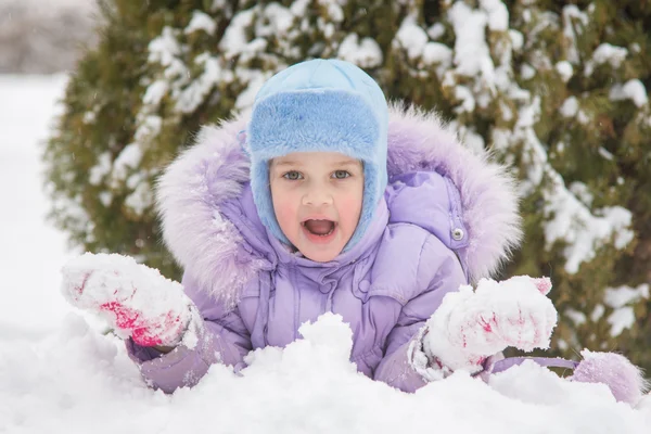 女孩躺在雪地里用雪球雪在手 — 图库照片