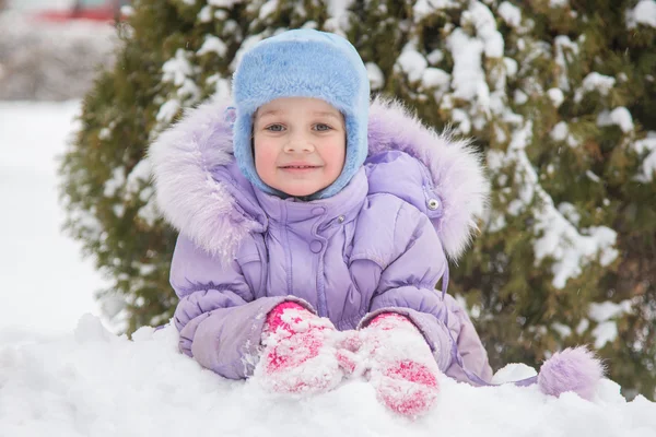 Flicka liggande i snön och snön leende — Stockfoto