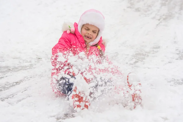 Fille roule sur une colline de neige fermé ses yeux sont sortis des bottes — Photo