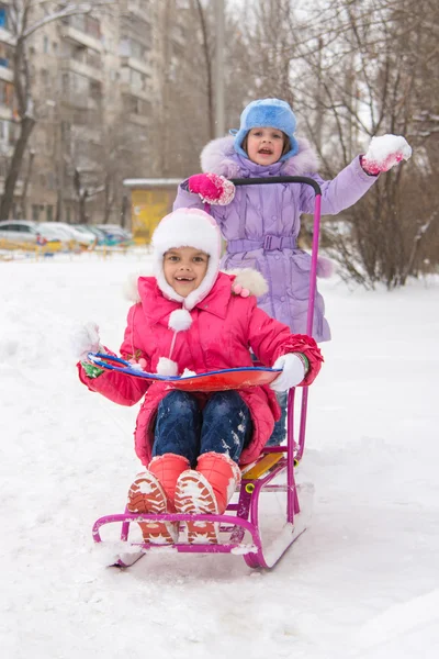 Le ragazze nel cortile di cavalcare una slitta di neve gioire — Foto Stock