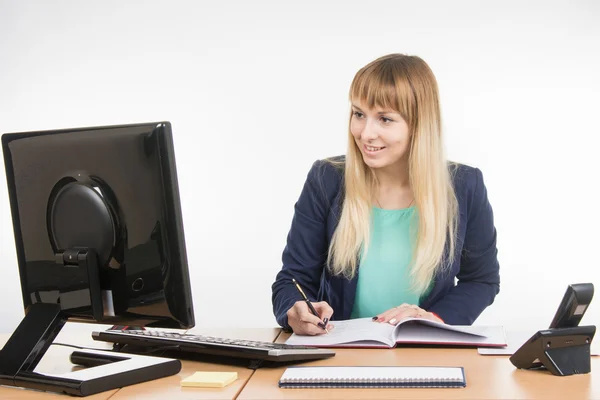 Zakenvrouw schrijven in een business-boek en keek op de monitor van de computer — Stockfoto