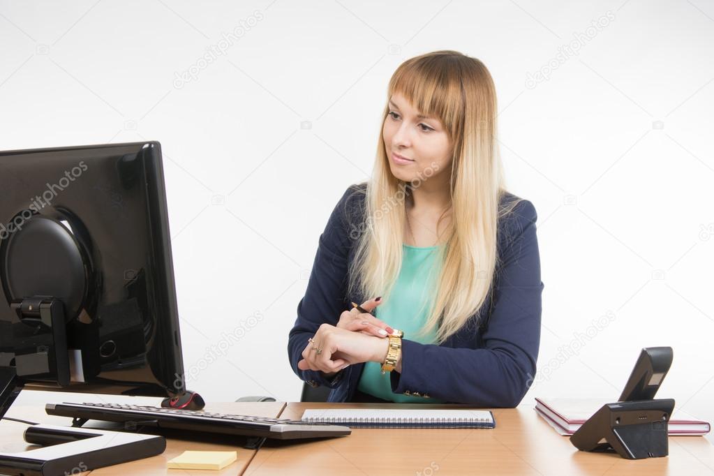 Business woman checks the time on a computer with a wristwatch
