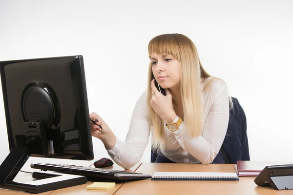 İş kadın konsantrasyonu ile telefonda konuşurken bilgisayarda çalışıyor — Stok fotoğraf