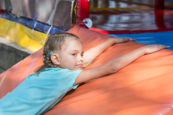 Six-year girl lies on a soft mat in front of the childrens room — Stock Photo, Image