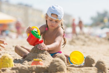 Dört yaşındaki bir kızın kum plaj sahil üzerinde oynamak