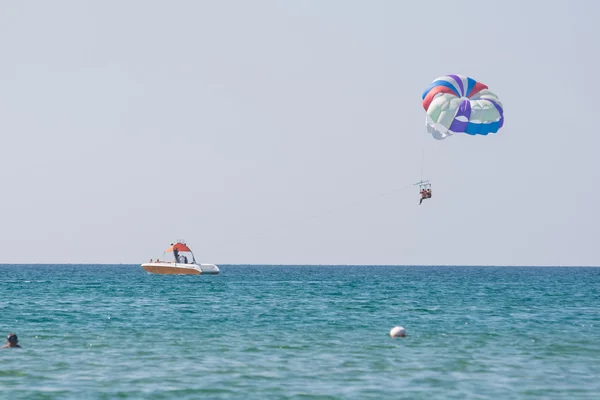 Offshore boat rolls of people on a parachute on the Black Sea coast — Stock Photo, Image