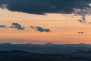 Dağların ve tepelerin üzerindeki manzara günbatımı renkleri. Turuncu, kırmızı, mavi, doğal güzelliği gölgeliyor. Kırsal, yazılı metinler için kopyalama alanı.