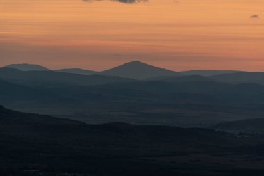 Dağların ve tepelerin üzerindeki manzara günbatımı renkleri. Turuncu, kırmızı, mavi, doğal güzelliği gölgeliyor. Kırsal, yazılı metinler için kopyalama alanı.