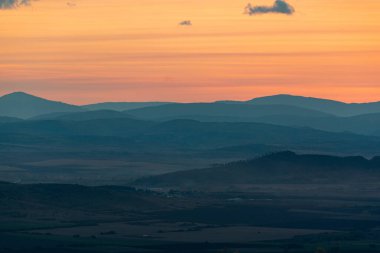 Dağların ve tepelerin üzerindeki manzara günbatımı renkleri. Turuncu, kırmızı, mavi, doğal güzelliği gölgeliyor. Kırsal, yazılı metinler için kopyalama alanı.
