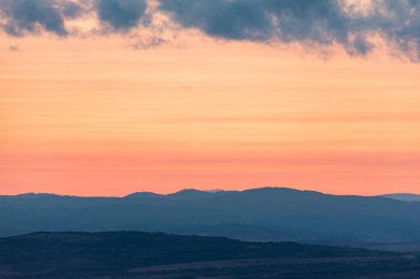 Dağların ve tepelerin üzerindeki manzara günbatımı renkleri. Turuncu, kırmızı, mavi, doğal güzelliği gölgeliyor. Kırsal, yazılı metinler için kopyalama alanı.