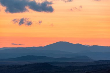 Dağların ve tepelerin üzerindeki manzara günbatımı renkleri. Turuncu, kırmızı, mavi, doğal güzelliği gölgeliyor. Kırsal, yazılı metinler için kopyalama alanı.