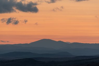 Dağların ve tepelerin üzerindeki manzara günbatımı renkleri. Turuncu, kırmızı, mavi, doğal güzelliği gölgeliyor. Kırsal, yazılı metinler için kopyalama alanı.
