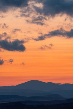Dağların ve tepelerin üzerindeki manzara günbatımı renkleri. Turuncu, kırmızı, mavi, doğal güzelliği gölgeliyor. Kırsal, yazılı metinler için kopyalama alanı.