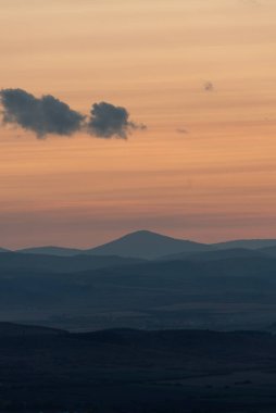 Dağların ve tepelerin üzerindeki manzara günbatımı renkleri. Turuncu, kırmızı, mavi, doğal güzelliği gölgeliyor. Kırsal, yazılı metinler için kopyalama alanı.