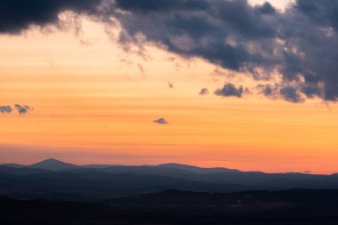 Dağların ve tepelerin üzerindeki manzara günbatımı renkleri. Turuncu, kırmızı, mavi, doğal güzelliği gölgeliyor. Kırsal, yazılı metinler için kopyalama alanı.