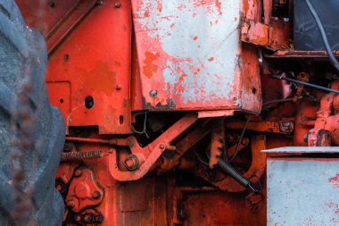 Hidrolik mekanizma kapanıyor ve eski paslı Rus traktörüne yağ yağı sonbahar hasat makinesi döşeniyor.