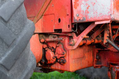 Hidrolik mekanizma kapanıyor ve eski paslı Rus traktörüne yağ yağı sonbahar hasat makinesi döşeniyor.