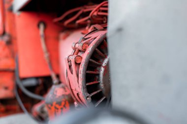 Dört silindirli dizel traktör motoru, görünür kemer izleri, paslı hidrolik parçalar ve güneşli sonbahar gününde kırmızı boya.