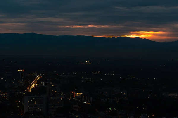Letzte Sonnenuntergangsstrahlen Zwischen Dunkelblauen Wolken Über Einer Stadt Der Berglandschaft — Stockfoto