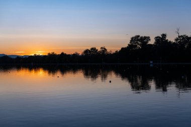 Gün batımının canlı yansımaları derin mavi su simetri silueti peyzaj parkı park kıyısı orman adasında metin için bir sürü kopya alanı ile birlikte
