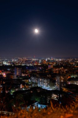 Büyük karanlık şehir ay ışığı ve binlerce küçük ışık ile aydınlandı tepenin zirvesinden gece yüksek görüş açısı