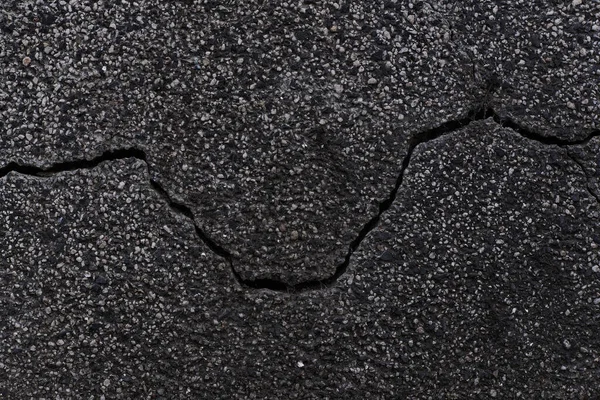Dark texture of old broken asphalt road or wall big abrasions cracks on the surface pebbles cement in Sofia, Bulgaria, Eastern Europe — Stockfoto