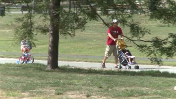 Vater schiebt Kinderwagen, während Sohn Fahrrad fährt (2 von 2)) — Stockvideo