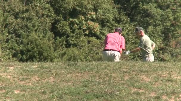 Due golfisti che praticano l'altalena nel grezzo — Video Stock