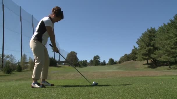 Vrouwelijke golfspeler dribbelt de bal uit tee — Stockvideo