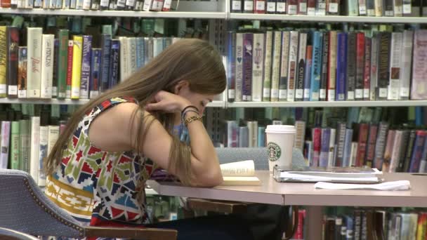 Молода дівчина з Starbucks кави вивчення в бібліотеці — стокове відео