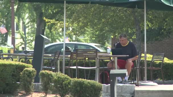 Pessoa sentada a uma mesa ao longo da calçada — Vídeo de Stock