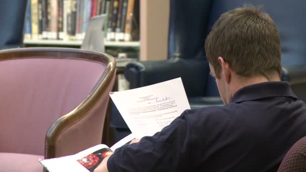 Hombre leyendo papeles en una biblioteca — Vídeos de Stock