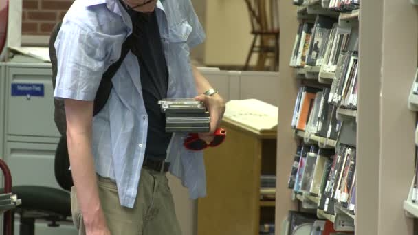 Студент дивлячись на Dvr в бібліотеці — стокове відео