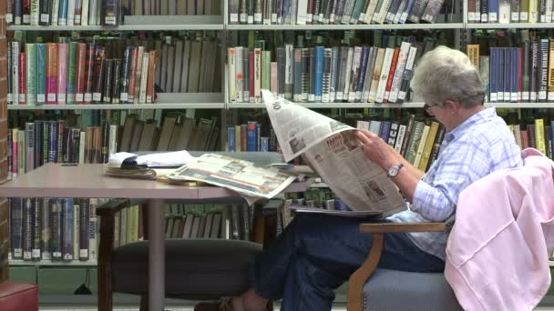 Mulher madura lendo um jornal na biblioteca (2 de 2 ) — Vídeo de Stock