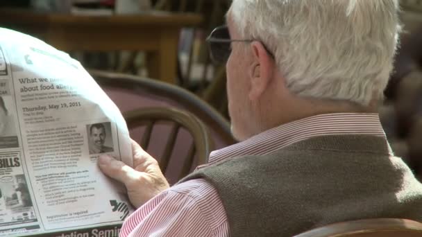 Oudere man lezen van de krant in de bibliotheek — Stockvideo