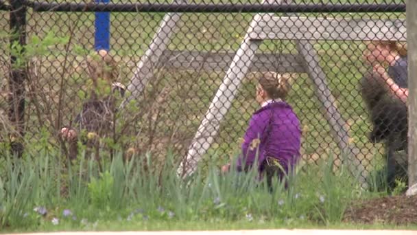 Enfants sur les balançoires comme on le voit à travers la clôture — Video