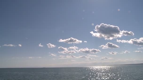Sun shining through puffy clouds on to the water — Stock Video