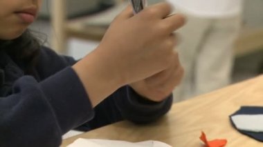 İlköğretim Okulu öğrencisi bir işaretleyici üzerinde kapağı almak çalışıyor