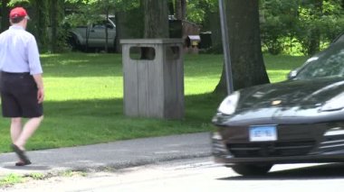 İnsanlar kaldırımdan bir park kenarı boyunca çöp dağıtıcısı tarafından