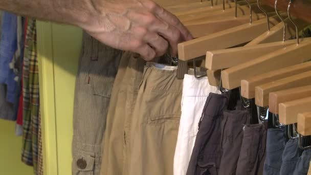 Мужчина смотрит на стойку для штанов в загородном магазине — стоковое видео