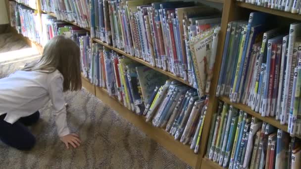 Kleines Mädchen beim Blick durch Kinderbuchreihen (1 von 4)) — Stockvideo