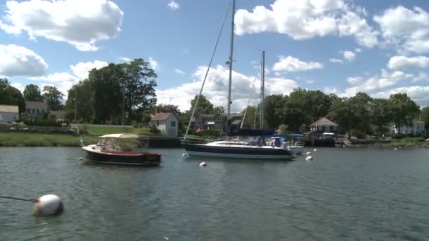 Riding by large sail boats moored in front of homes. — Stock Video