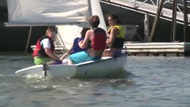 Quatre personnes à bord d'un petit voilier accostant à quai . — Video