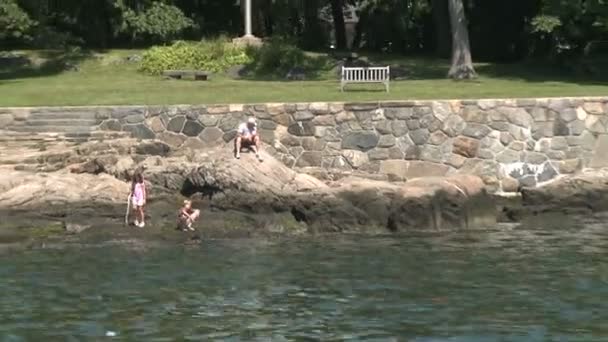 Niños jugando en las rocas en la orilla . — Vídeos de Stock