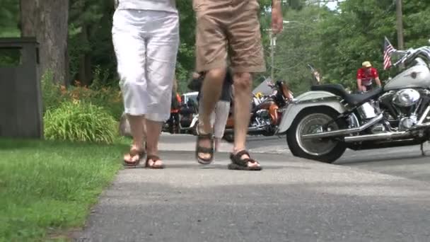 Пара прогулок по тротуару вдоль припаркованных мотоциклов (2 из 2 ) — стоковое видео