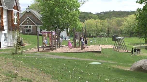 Crianças em baloiços em pequeno parque infantil — Vídeo de Stock