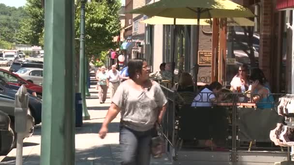 Люди проходят мимо маленького кафе на тротуаре . — стоковое видео