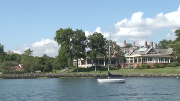 Stort hus på vannet med liten seilbåt foran . – stockvideo