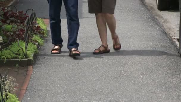 Två personer med sandaler på stopp framför en butik — Stockvideo